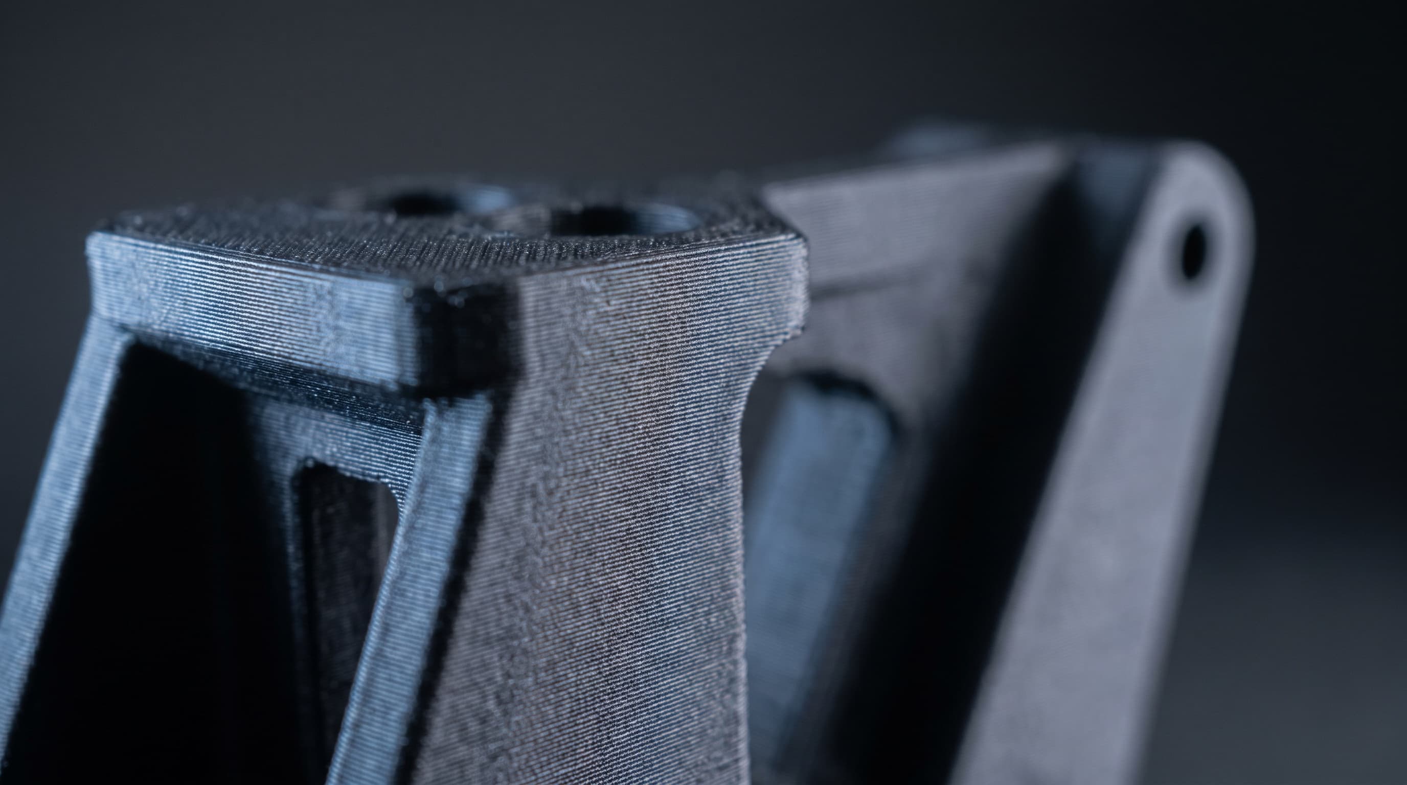 Gros plan sur une équerre imprimée en 3D, les couches d'impression visibles sous une lumière rasante.